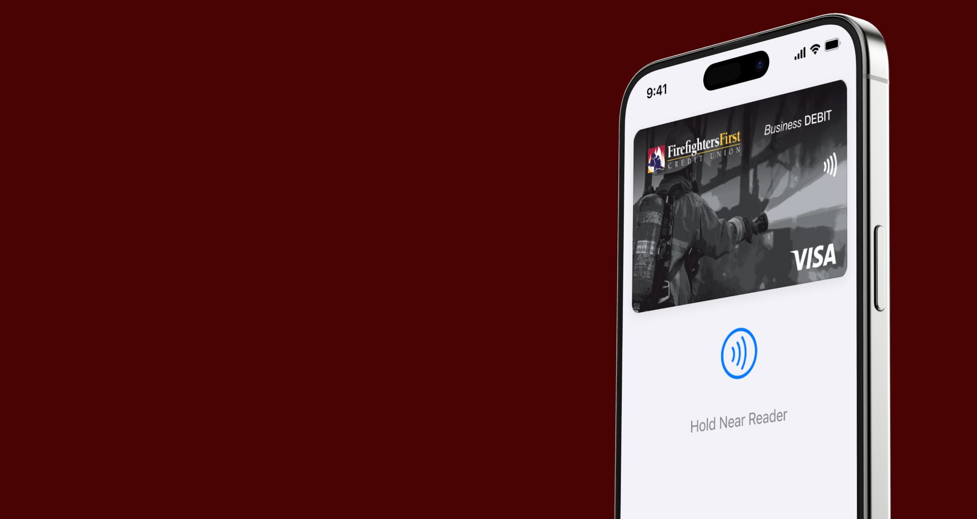 A iPhone on a red background, with a photo of a Firefighters First business debit card on the screen, and an icon that directs the user to "Hold Near Reader"