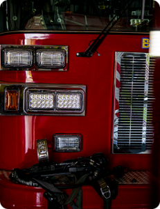 A closeup of the front of a fire engine inside the bay, with the headlights and grille visible
