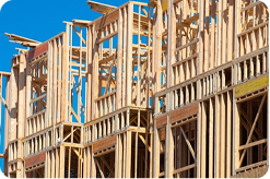A photo of wooden frame construction, two stories tall, with openings for windows.