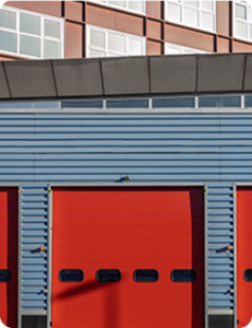 An exterior view of a blue fire station with three red bay doors, all closed.