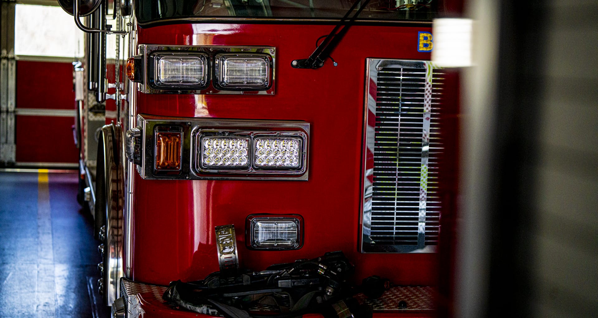 A closeup of the front of a fire engine inside the bay, with the headlights and grille visible