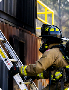 A fireman preparing to climb a ladder op the side of a burned out container