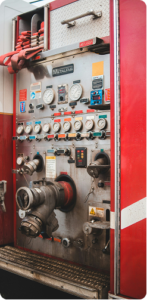 A photo of a fire engines hose connections and gauges, with folded hoses stored,