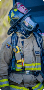 Firefighter in full gear, outside, looking up and to the right.