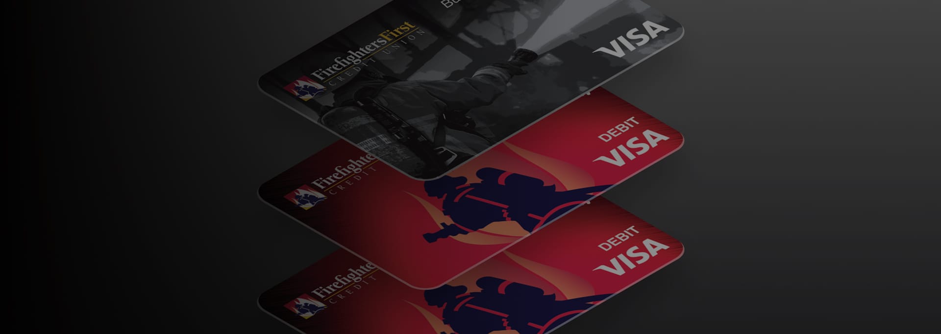 Stack of Firefighters First Credit Union debit cards, including a dark-themed card on top and red cards underneath, shown against a shadowed background.