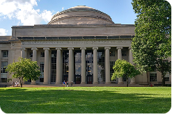 Large domed academic building with tall columns and a grassy lawn in front, framed by trees.