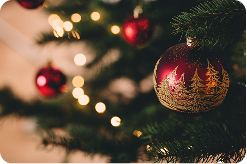 Close-up of a Christmas tree with red ornaments and warm white lights in soft focus.