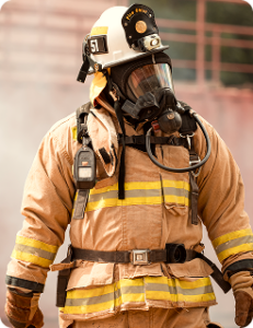 Firefighter wearing full protective turnout gear and breathing apparatus standing outdoors.