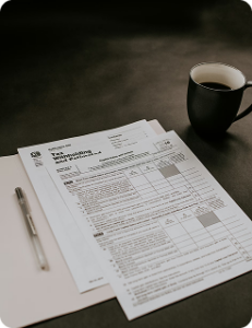 A photo of tax documents ready to be filled our, on a table with a pen and mug of coffee