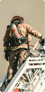 Firefighter climbs a metal ladder in full gear, with an air tank on their back against a clear sky.