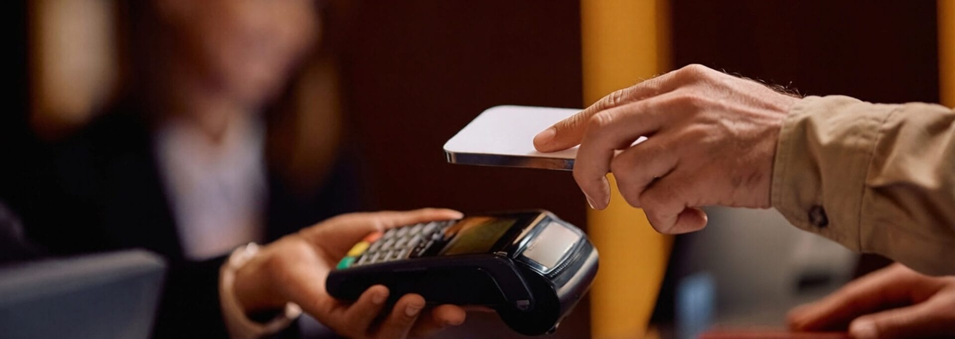 Person tapping a smartphone on a payment terminal to complete a contactless transaction