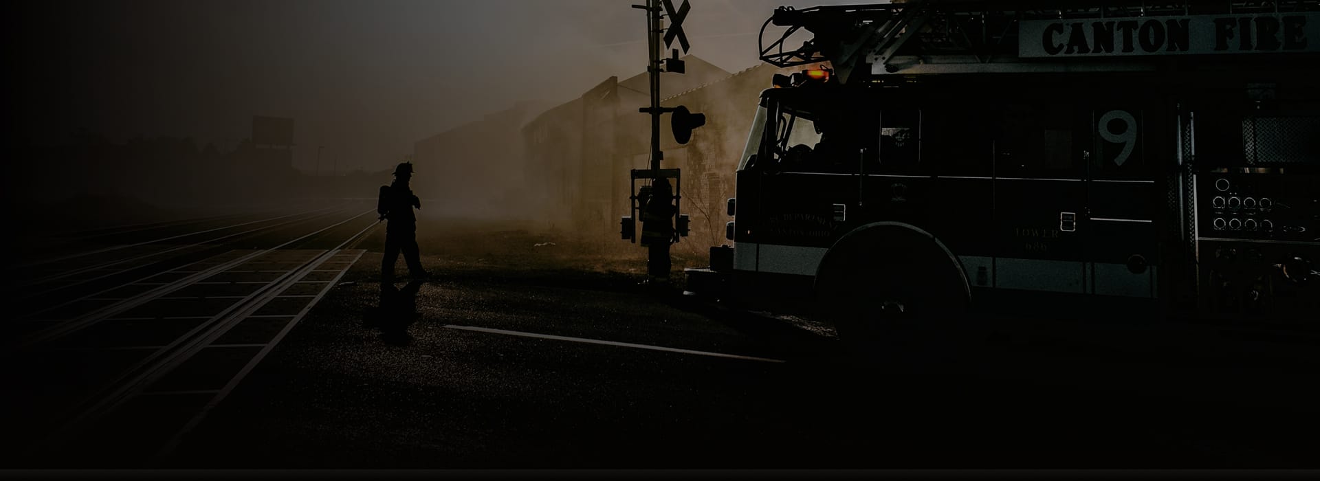Fire engine stopped by railway tracks, with a firefighter silhouetted against the background