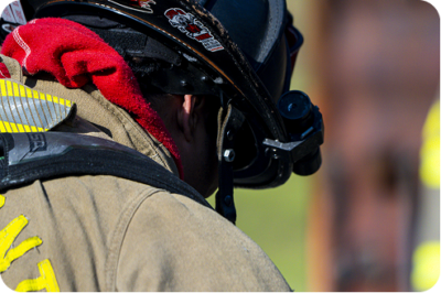 Close-up rear view of a firefighter in a helmet and turnout gear collar