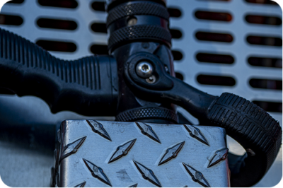 Close-up of fire truck step hardware showing diamond-plate surface and hose bracket fittings