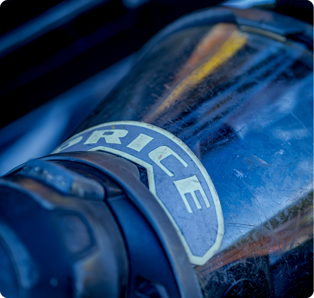 Close-up of a worn blue SCBA tank with a name badge label and yellow stripe