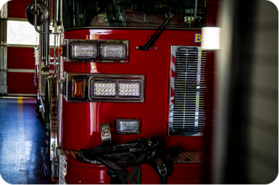 Front view of a red fire engine parked inside a firehouse bay