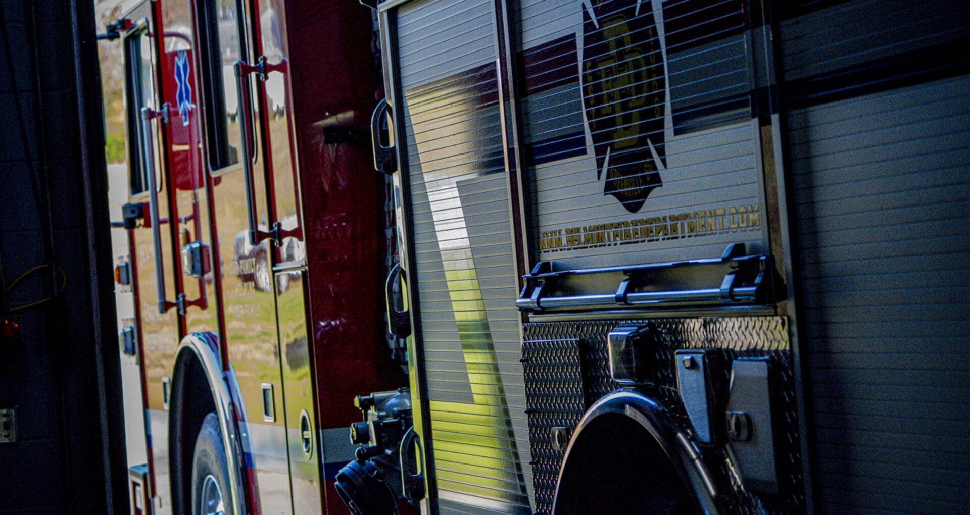 Side view of two fire department vehicles parked side by side showing department graphics and equipment compartments