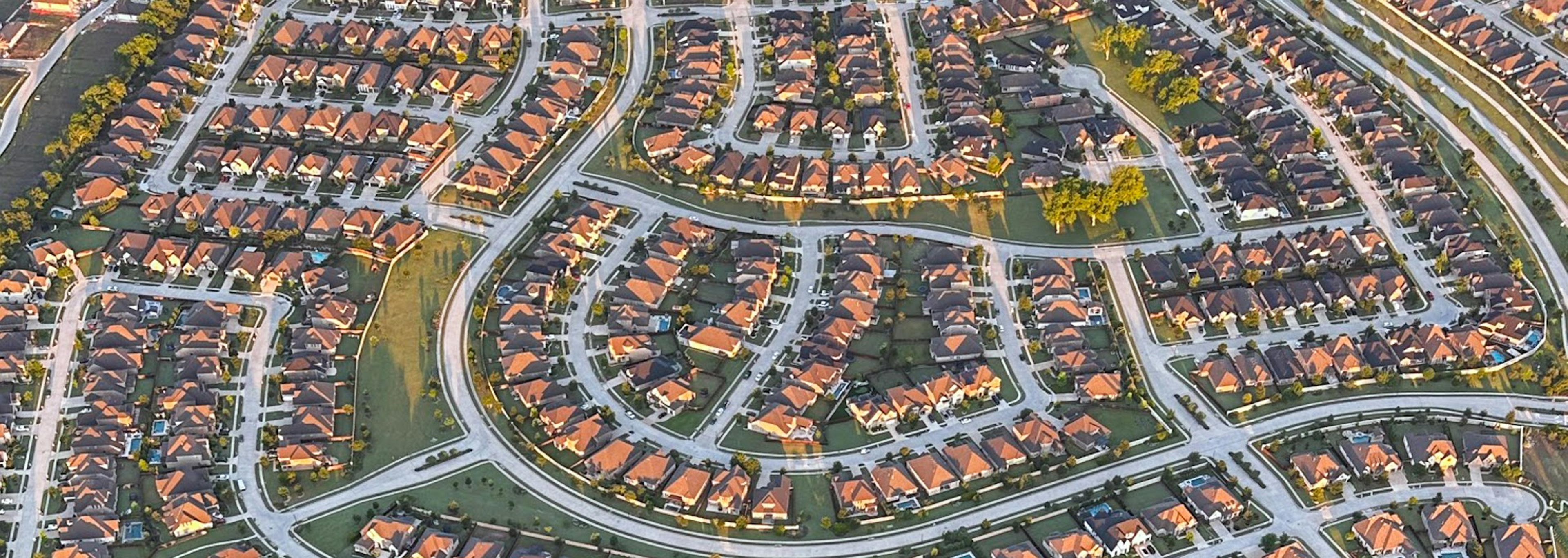 Aerial view of a residential neighborhood at sunset with mountains in the background
