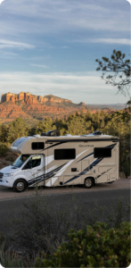 RV motorhome parked on a scenic overlook with red rock formations in the background