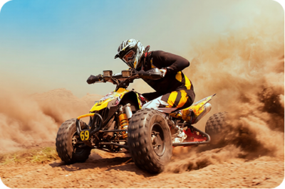 Rider on a yellow and black ATV kicking up dust on a dirt trail