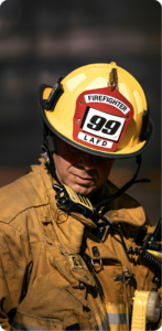 Close-up of an LAFD firefighter in full gear wearing a yellow helmet marked Firefighter 99