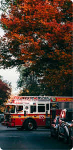 Ladder Company 122 fire truck parked beneath autumn foliage with emergency lights on