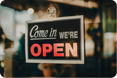 "Come in, we're open" sign displayed in a storefront window