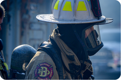 Belmont FPD firefighter in full turnout gear and SCBA mask at an active fire scene