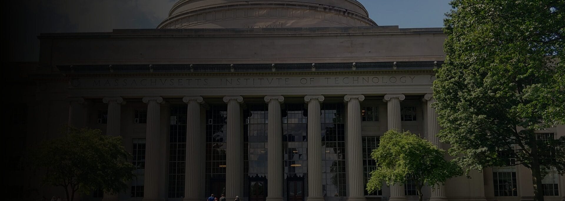 Stately white stone college building with pillars at the entrance.
