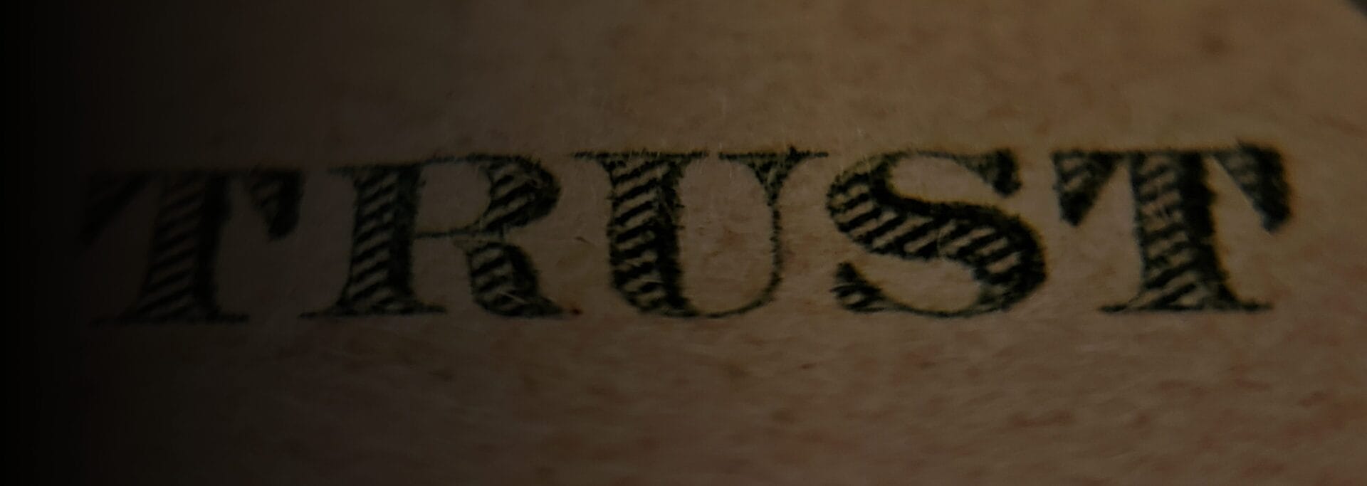 Close-up of the word "Trust" printed in ornate serif lettering on aged paper
