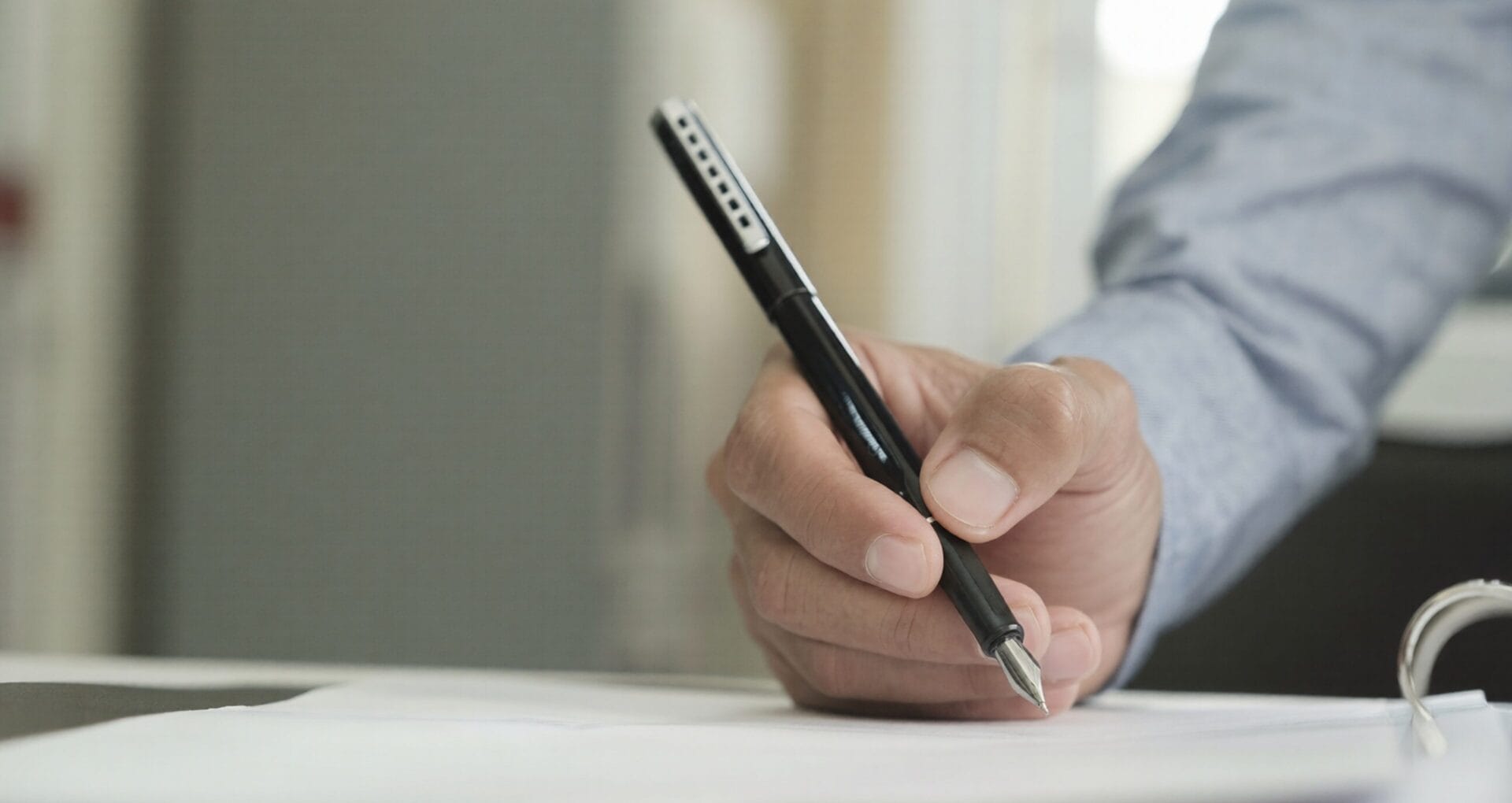 Close-up of a hand holding a fountain pen and signing a document