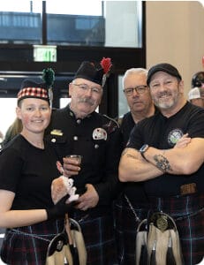 Four firefighters, wearing kilts and holding bagpipes
