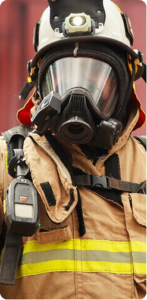 Firefighter in full turnout gear and oxygen mask, looking at the camera