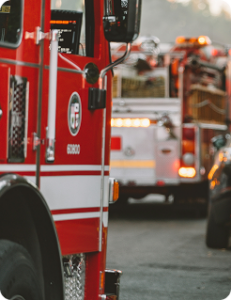 Multiple fire engines parked in a street, heavy smoke visible