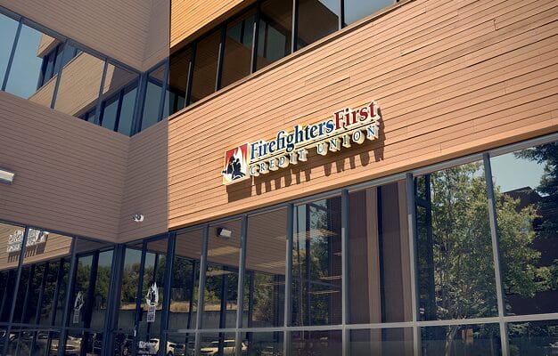 Exterior of the Firefighters First Credit Union Walnut Creek branch, featuring a modern building with warm wood siding and the FFCU logo and wordmark mounted above large glass windows.