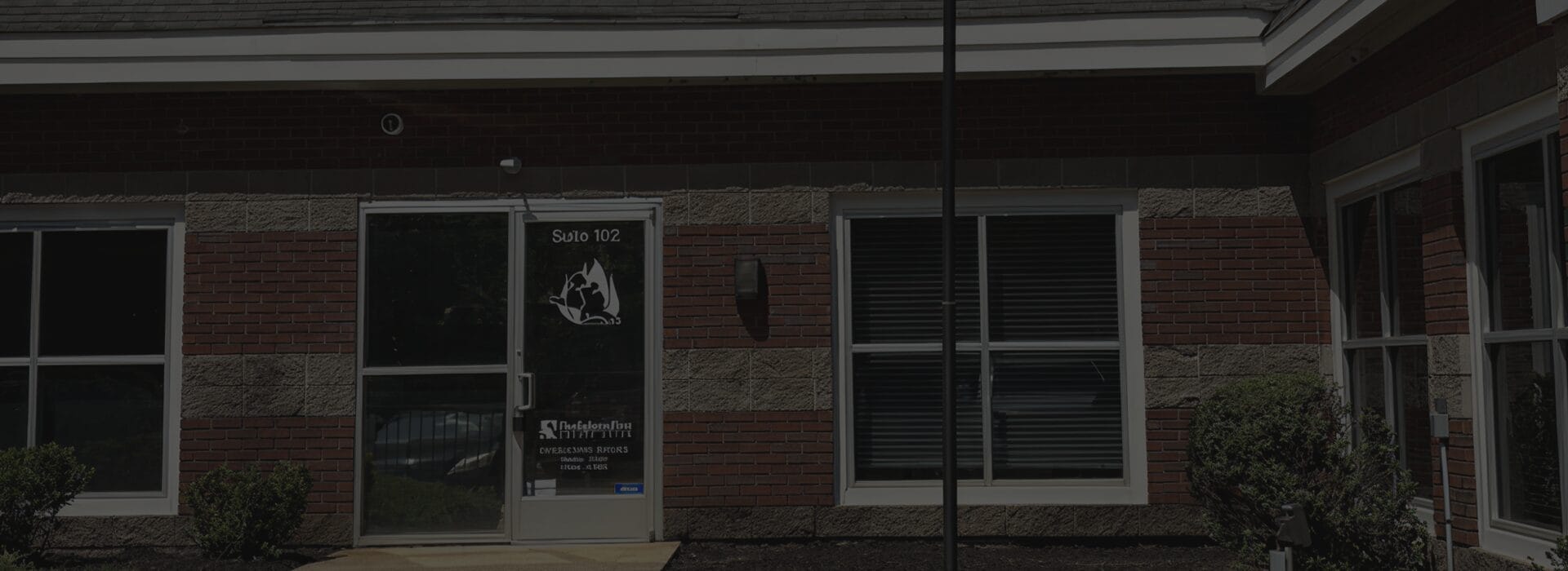 Exterior of the Firefighters First Credit Union Memphis branch, a brick and stone building with the FFCU logo decal on the glass door marked Suite 102.