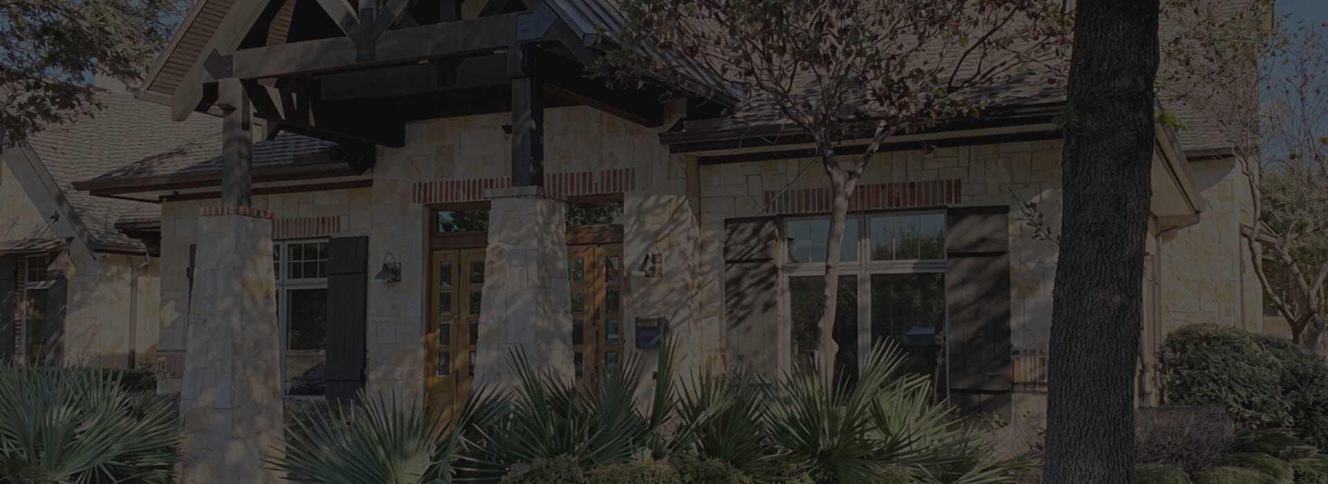 Exterior of the Firefighters First Credit Union Garland branch, a single-story Texas Hill Country style building with limestone columns, wood beam accents and native landscaping.